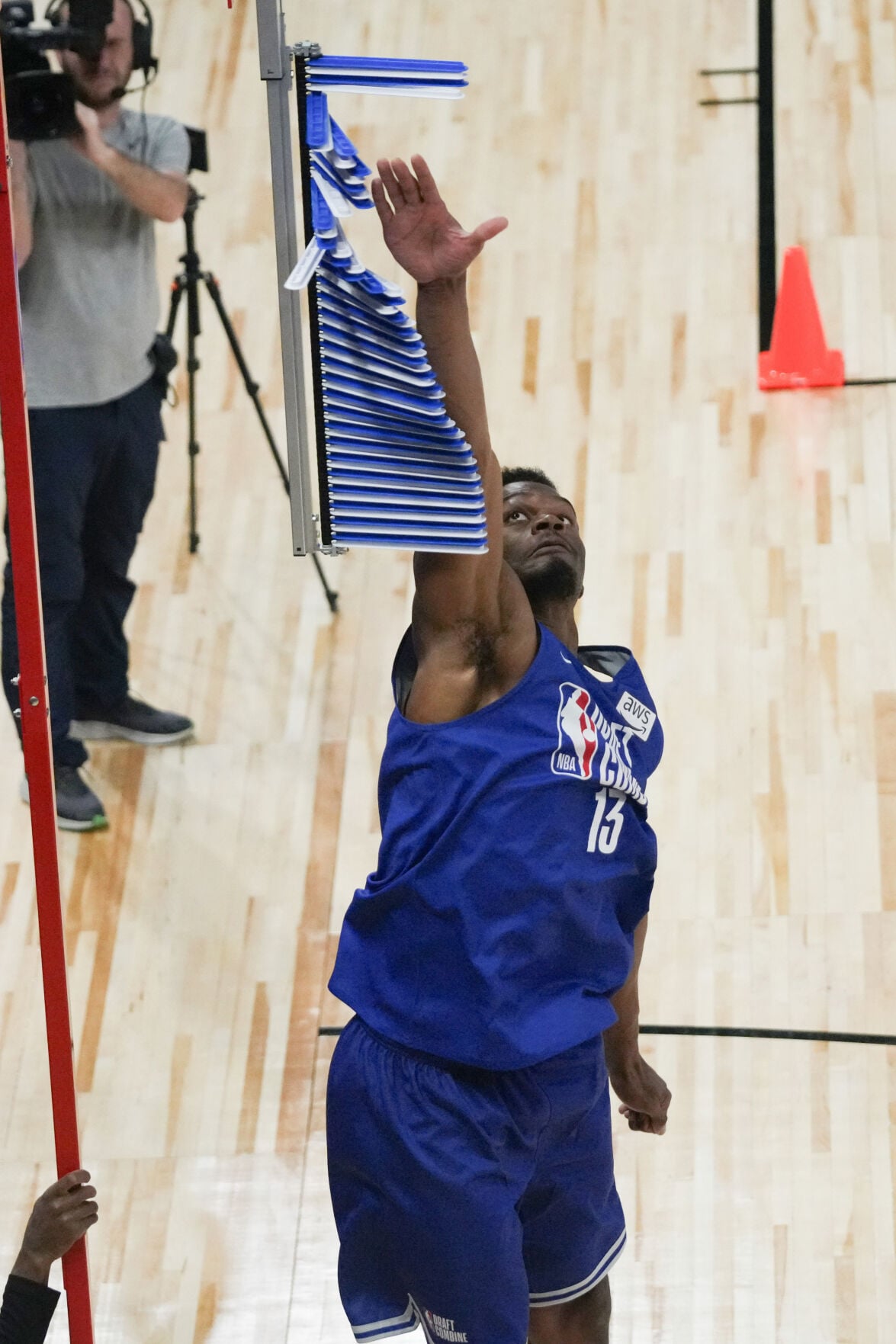 Tobe Awaka reaches up during a vertical reach test at the NBA Draft Combine, wearing his combine workout jersey (No. 13).