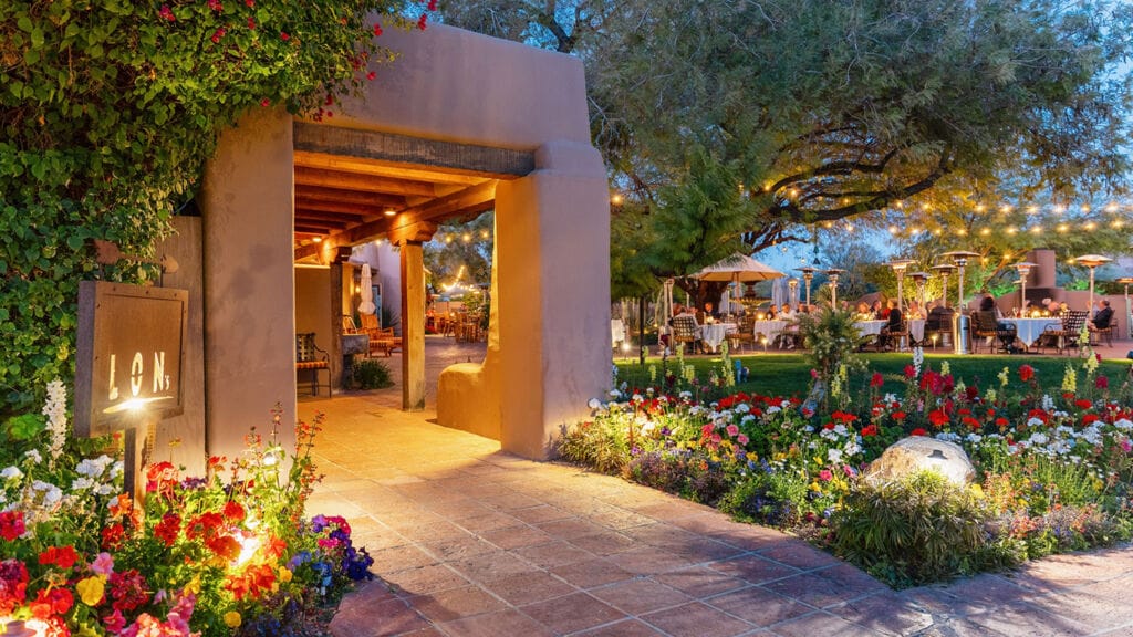 Southwestern-style entrance and garden dining lit with string lights and candles — an example of the intimate, romantic ambiance voters rewarded in Ranking Arizona’s 2026 list.