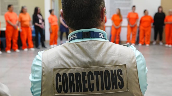 A corrections officer watches detainees in orange jumpsuits; the New River couple were ordered to prison after convictions in the Medicaid fraud scheme.