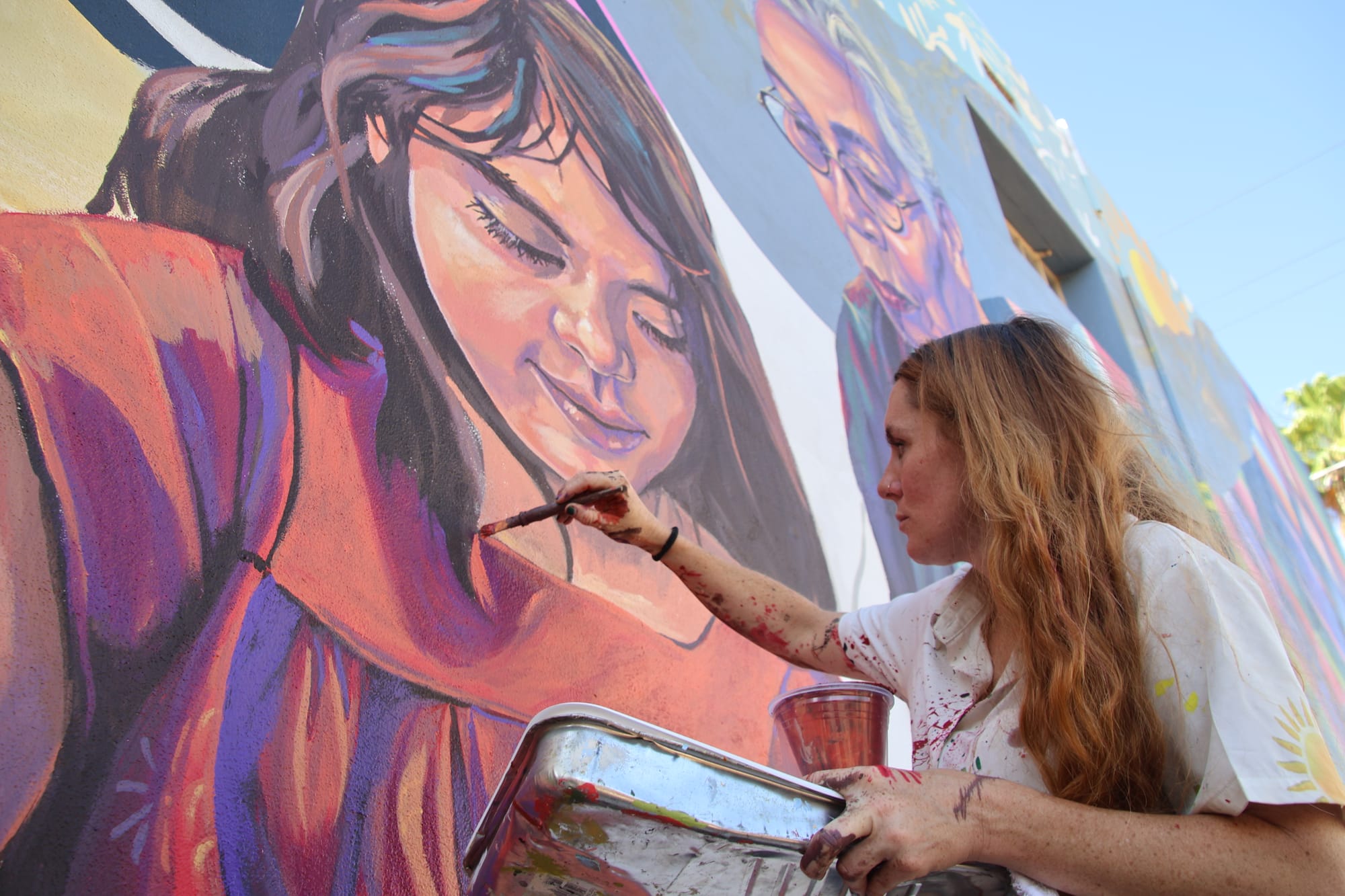 A muralist adds final brushstrokes to a painted figure during Rio Nuevo’s May 21 watch party as the public looked on while artists completed the downtown Tucson mural.