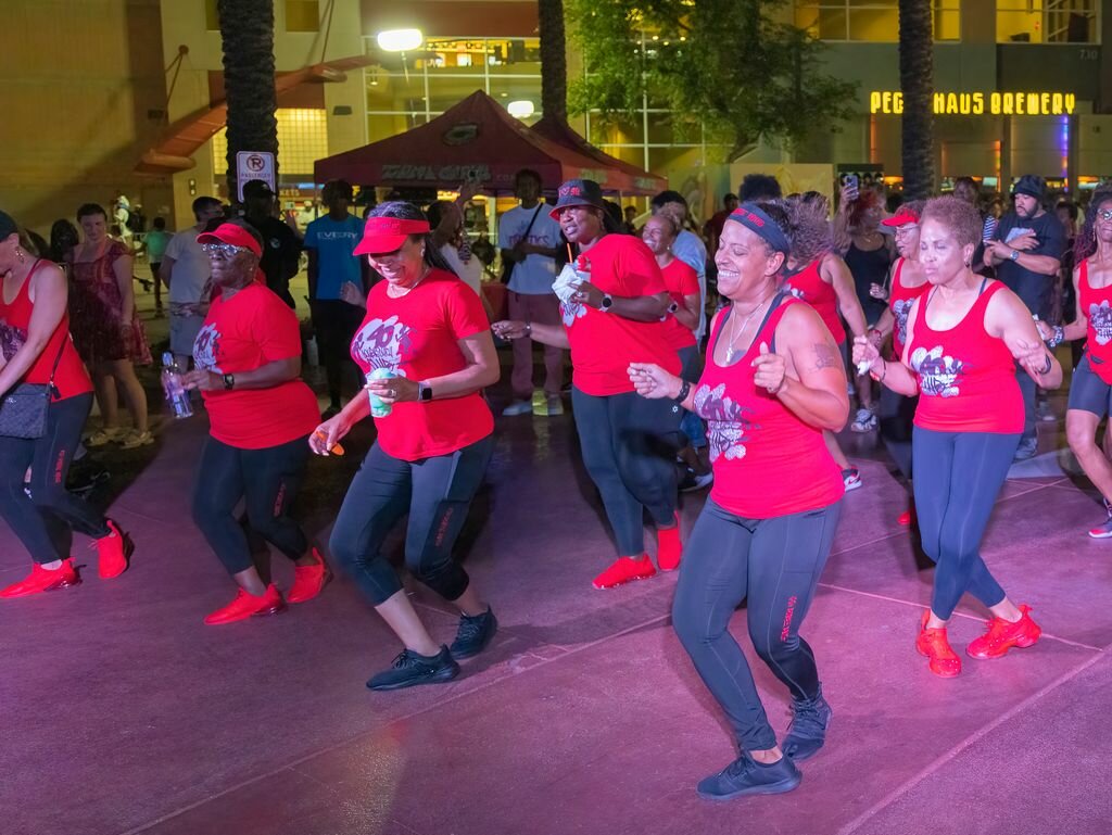 A group of dancers in matching red shirts performs at a nighttime Juneteenth celebration in Tempe, part of community events to raise awareness about the holiday.