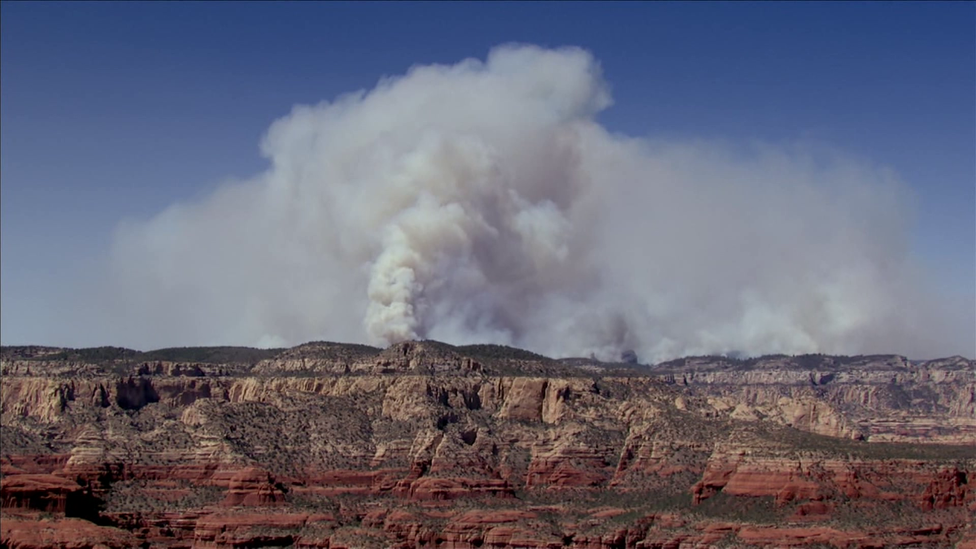 A large smoke plume rises over red‑rock terrain near Sedona from the Pocket Fire, one of the wildfires crews are working to contain as officials stage resources statewide.