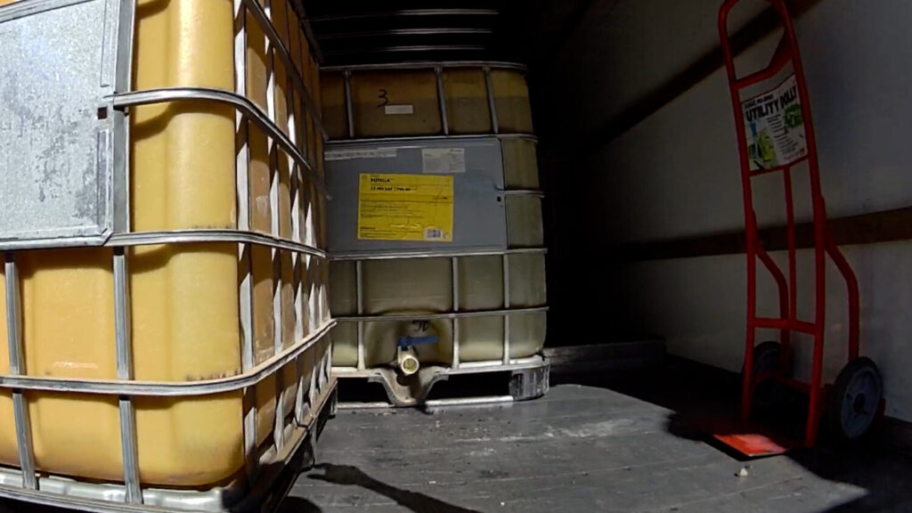 Large plastic fuel totes and a hand truck inside a trailer, shown by deputies as recovered fuel containers tied to the alleged theft of about 2,100 gallons of diesel.