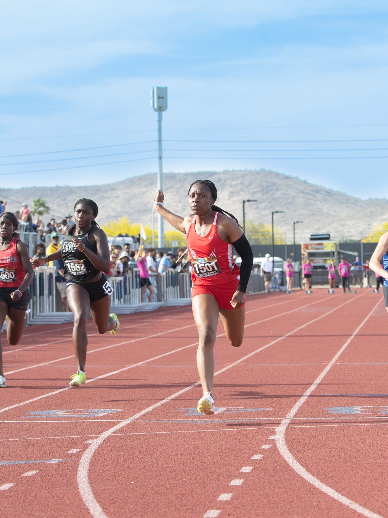Runners sprint toward the finish at an AIA track meet, where only top finishers earn qualifying spots for the state championships.