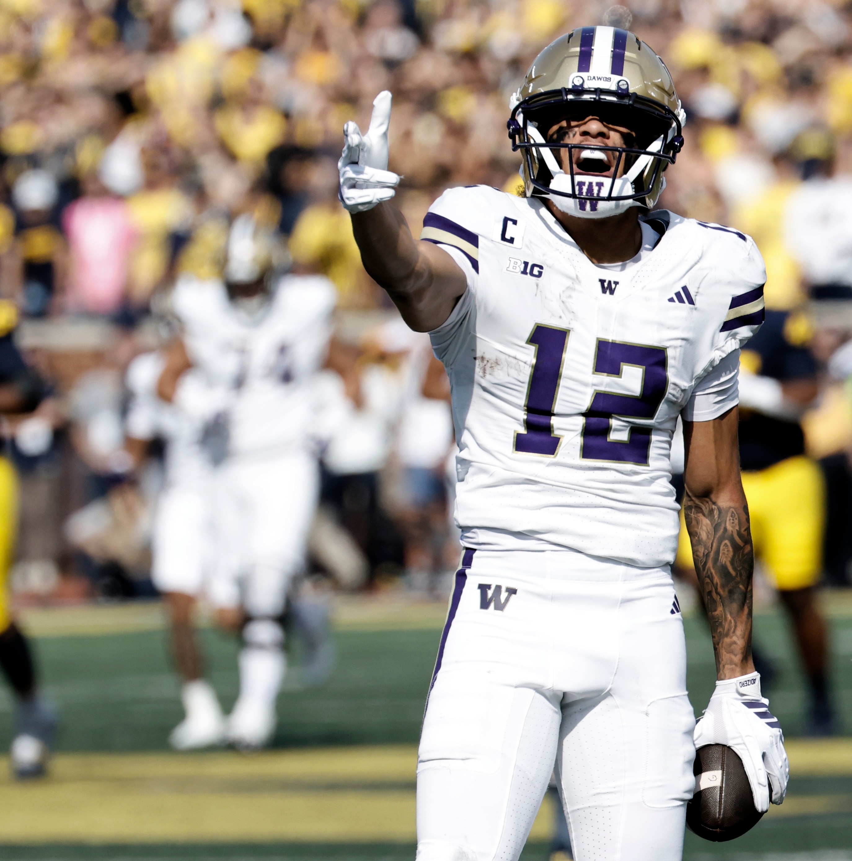 A Washington Huskies player in purple-and-gold celebrates on the field — team imagery to accompany UW signing a 4-star receiver from Arizona.