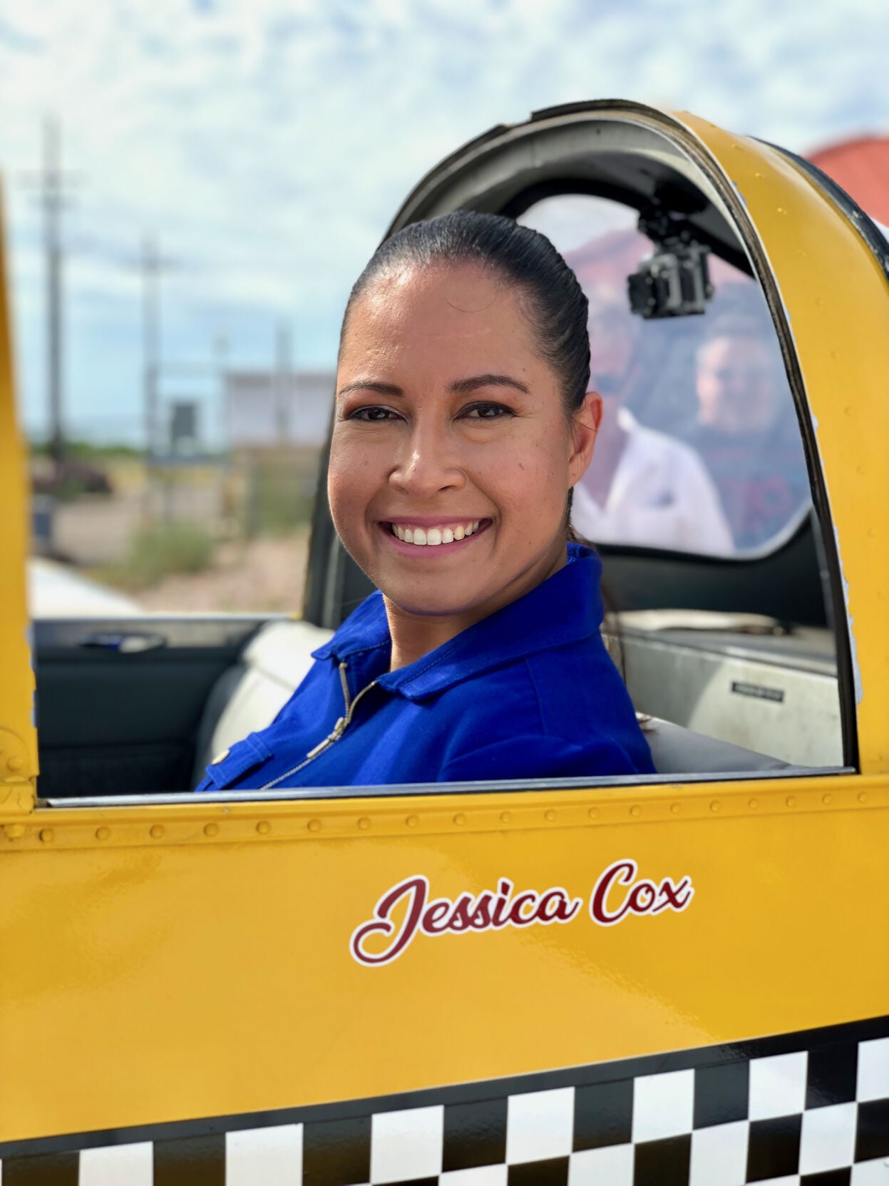 Smiling portrait of the armless pilot seated in the cockpit of her yellow plane at the event honoring her induction into the Arizona Aviation Hall of Fame.