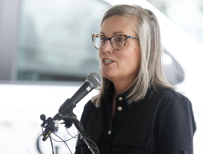 A candidate speaking into a microphone at a Tucson debate event addressing issues including data centers and housing.