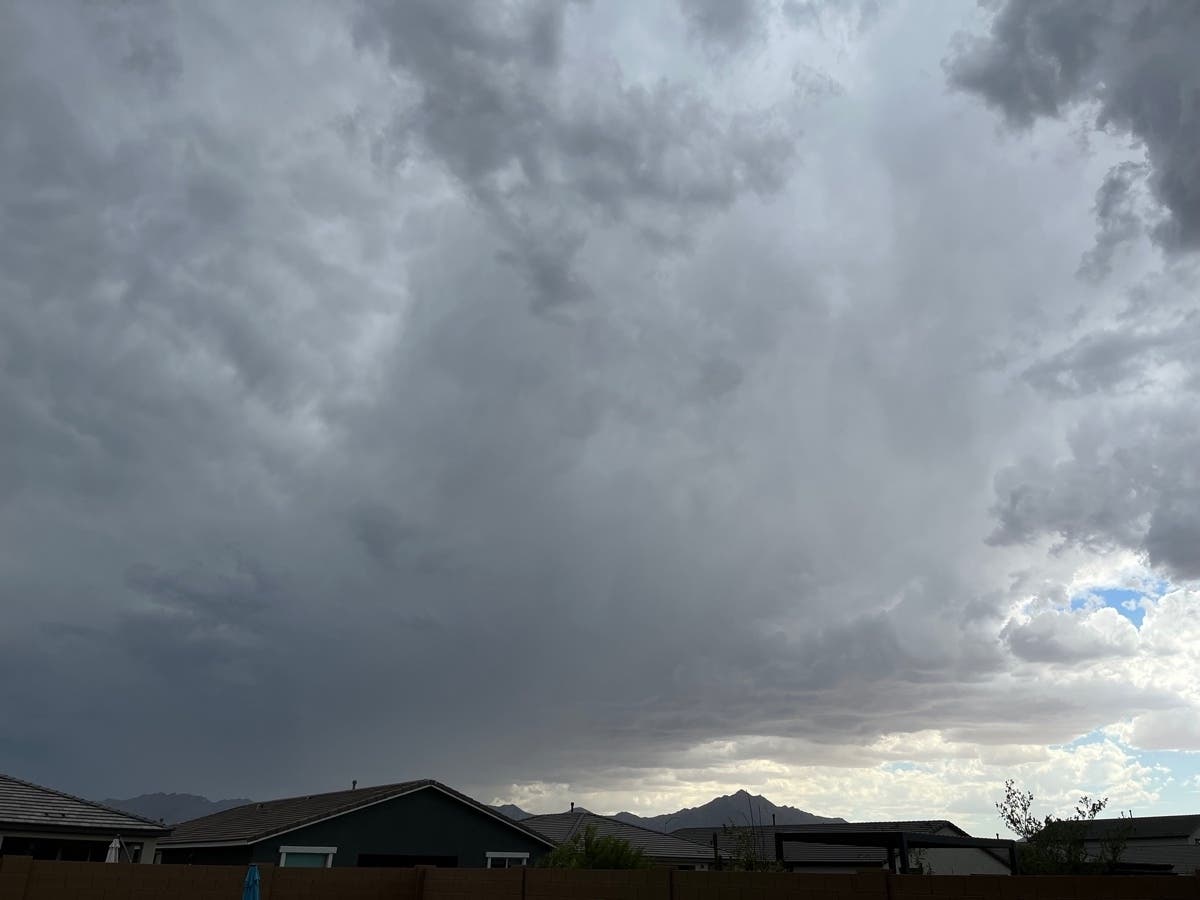 Thunderstorm clouds building over a Tucson-area neighborhood with mountains in the distance, illustrating increased midweek storm chances described in the report.