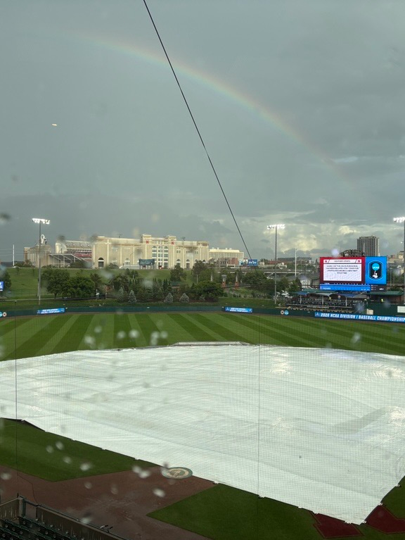 A rain-covered field and tarp at Nebraska's home ballpark — the weather-threatened setting where ASU's offense eventually secured the victory as the Sun Devils move on to a rematch with Ole Miss.