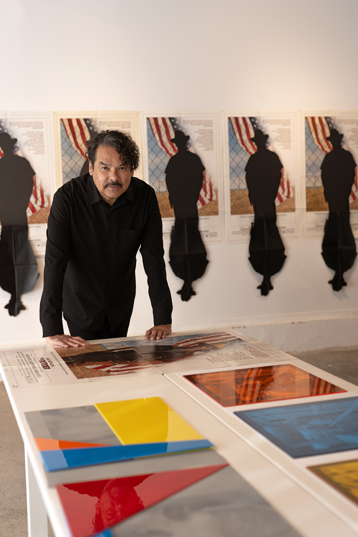 An artist stands among prints and silhouette works in a gallery at MOCA Tucson, illustrating the museum’s focus on exhibitions that prompt dialogue and healing.
