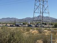 High-voltage transmission tower and power lines near the area, illustrating the electrical infrastructure tied to the outage that closed the mail center's retail lobby.